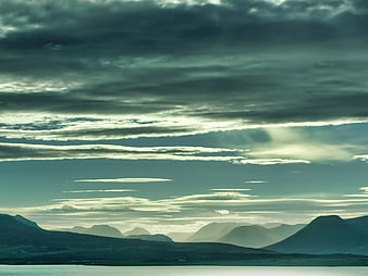 Dramatic moody mountain landscape with layered clouds and water