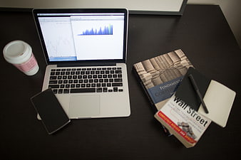 Laptop with finance books and coffee on desk