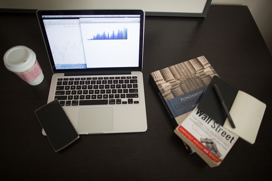 Laptop with finance books and coffee on desk