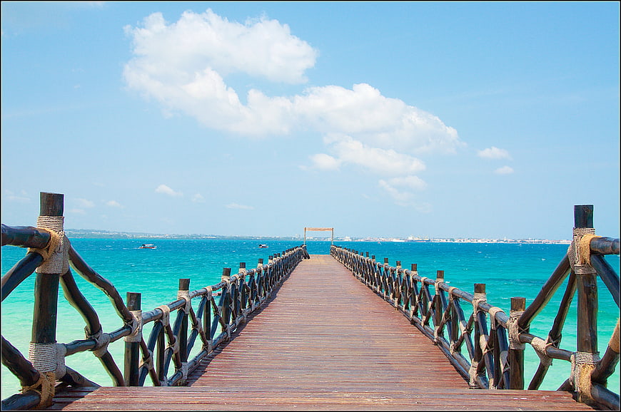 Wooden pier extending into turquoise ocean water under a blue sky