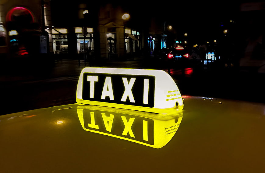 Illuminated Taxi Sign on Yellow Car Roof at Night