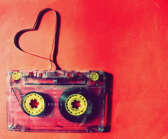 Clear cassette tape with magnetic tape shaped into a heart on red background