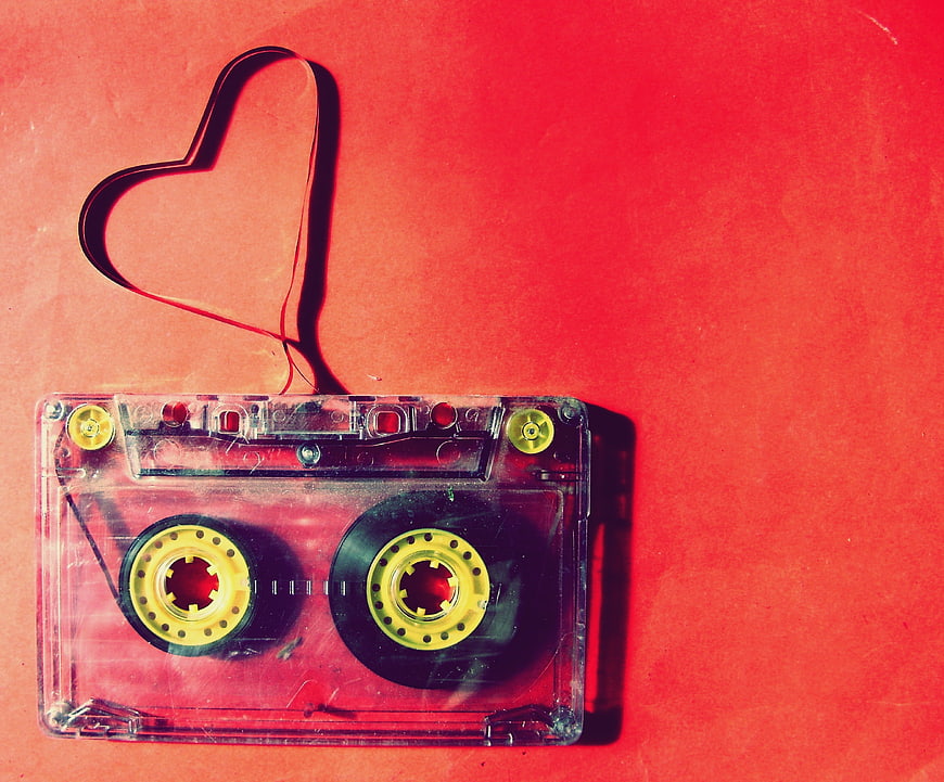 Clear cassette tape with magnetic tape shaped into a heart on red background