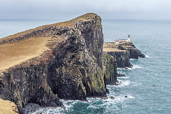 Dramatic coastal cliffs with lighthouse and ocean waves