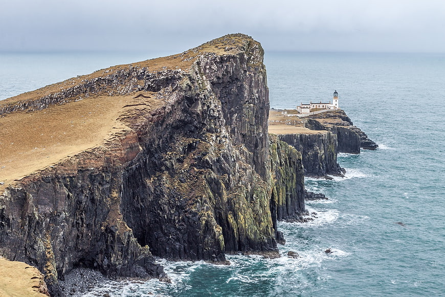 Dramatic coastal cliffs with lighthouse and ocean waves