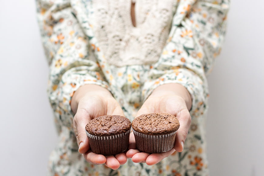Woman Holding Two Chocolate Muffins in Hands