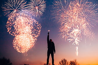 Silhouette of Man Holding Sparkler Under Fireworks