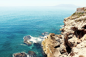 Sunny coastal cliff view with turquoise sea and wooden railing
