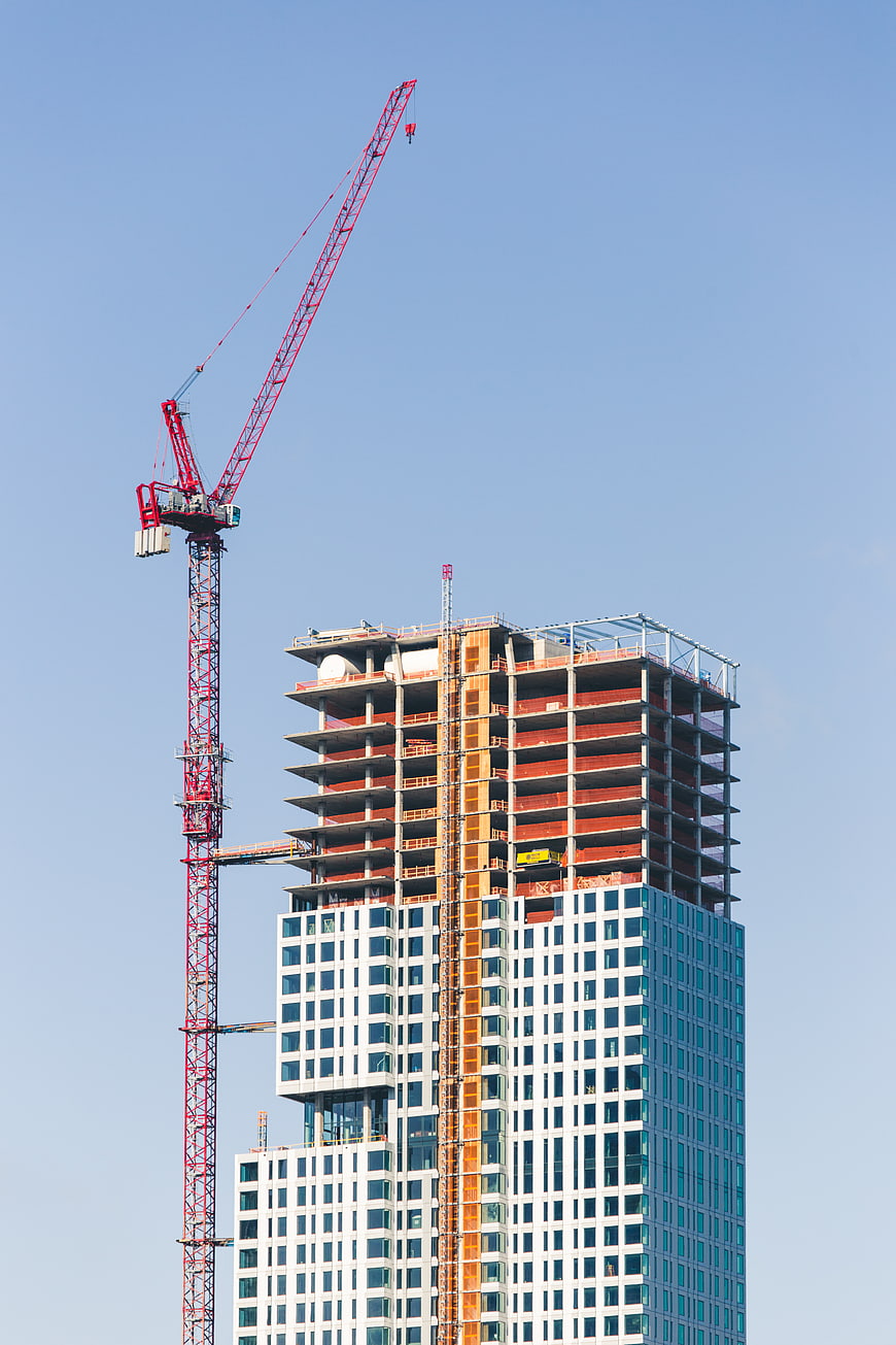Red Crane and Skyscraper Under Construction Against Blue Sky