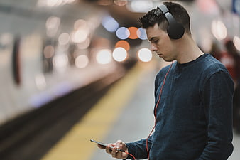 Young Man Listening to Music on Smartphone at Subway Station