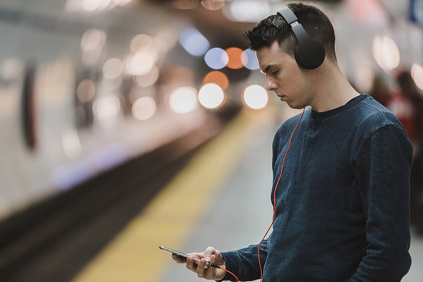 Young Man Listening to Music on Smartphone at Subway Station