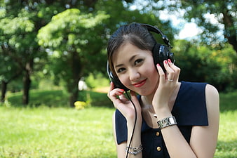 Young Woman Listening to Music with Headphones in Park