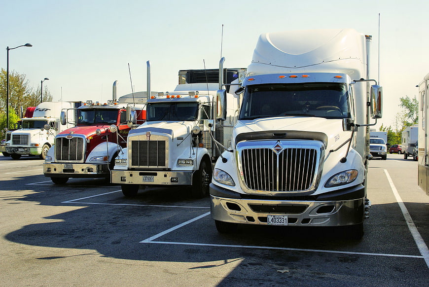 Row of parked semi-trucks in a sunny lot
