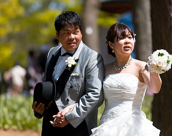 Asian wedding couple holding hands outdoors in spring