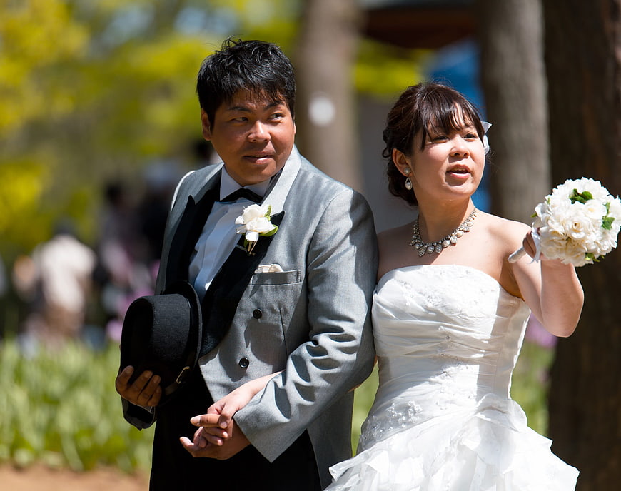 Asian wedding couple holding hands outdoors in spring