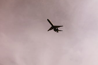 Airplane flying against a moody purple cloudy sky