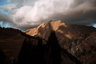 Dramatic Mountain Peak Illuminated by Sunlight Through Clouds