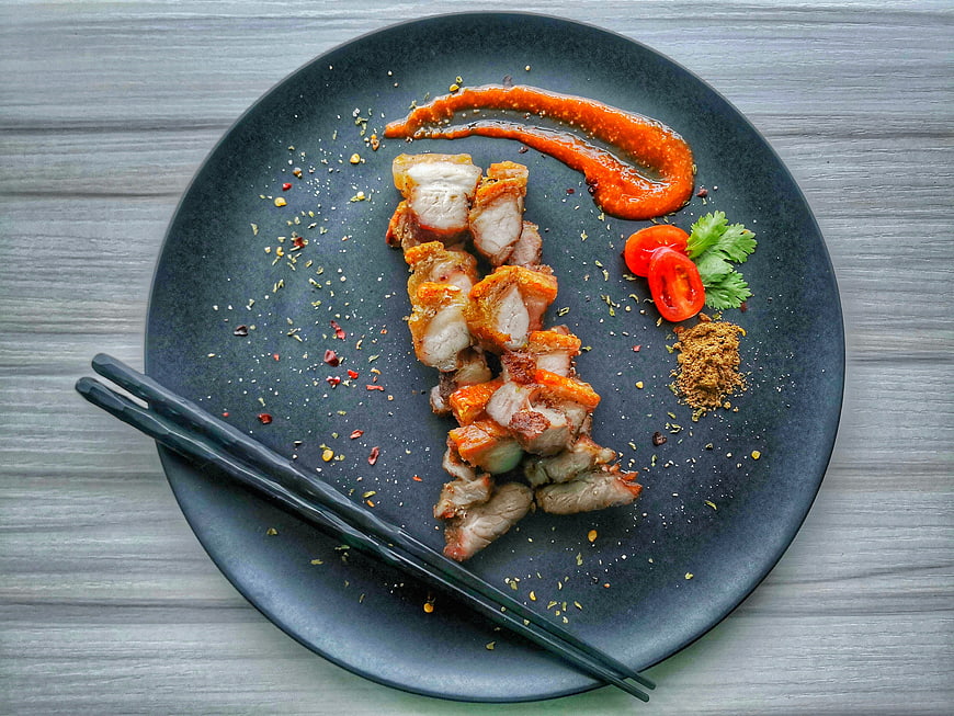 Roasted Pork Belly on Black Plate with Sauce and Garnish