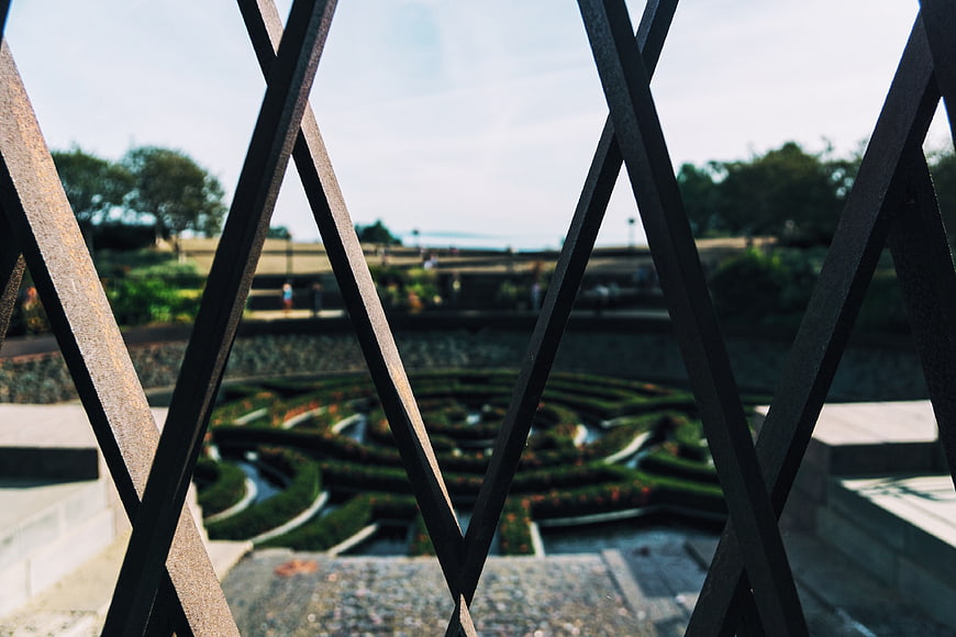 View of formal garden maze through black metal railing