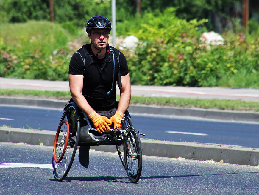 Athletic Man Riding Racing Wheelchair On Asphalt Road