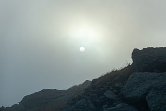 Sun Shining Through Fog Over Rocky Mountain Ridge
