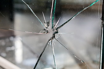 Close-up of shattered glass with impact point and cracks