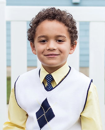 Portrait of young boy in school uniform with argyle sweater