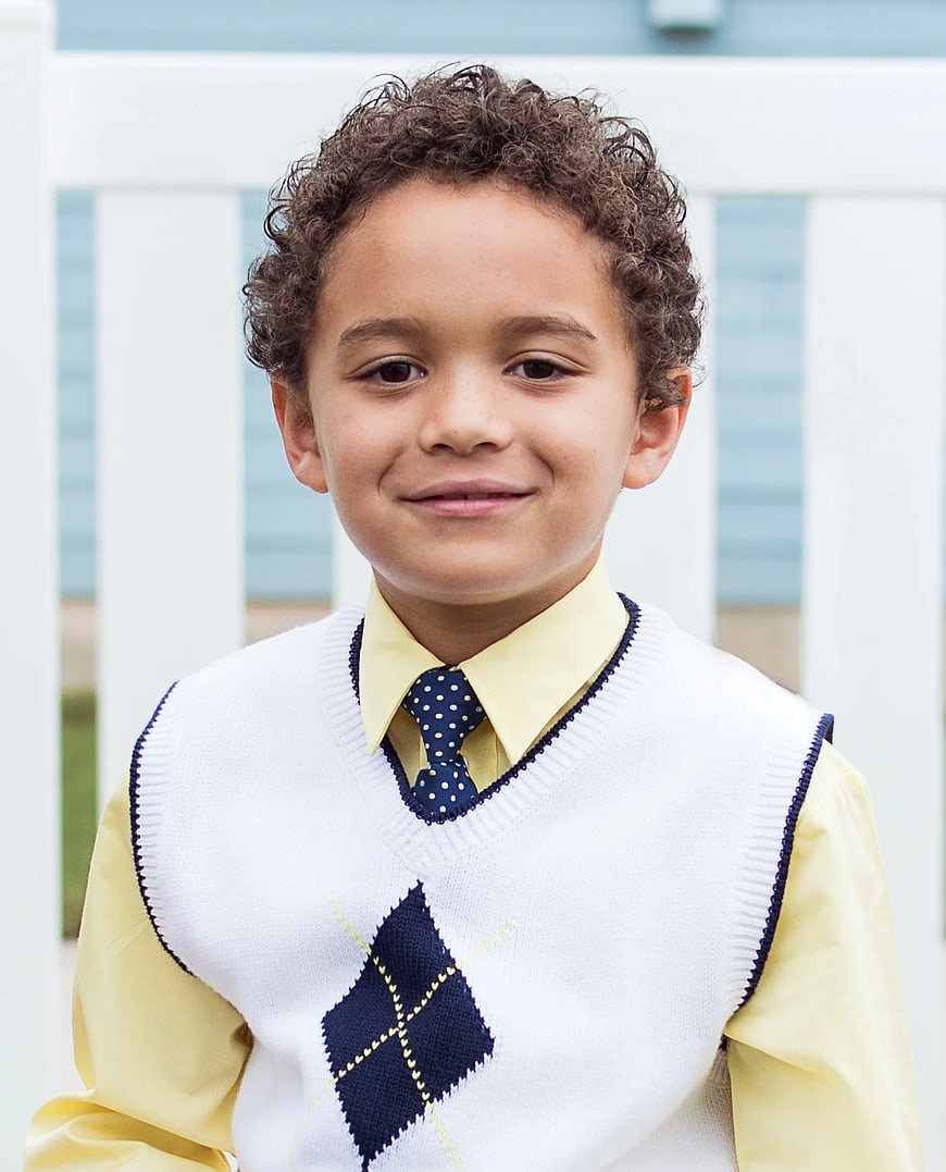Portrait of young boy in school uniform with argyle sweater