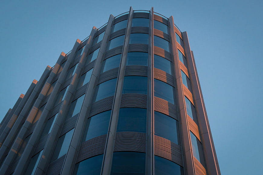 Modern curved glass skyscraper facade against blue sky