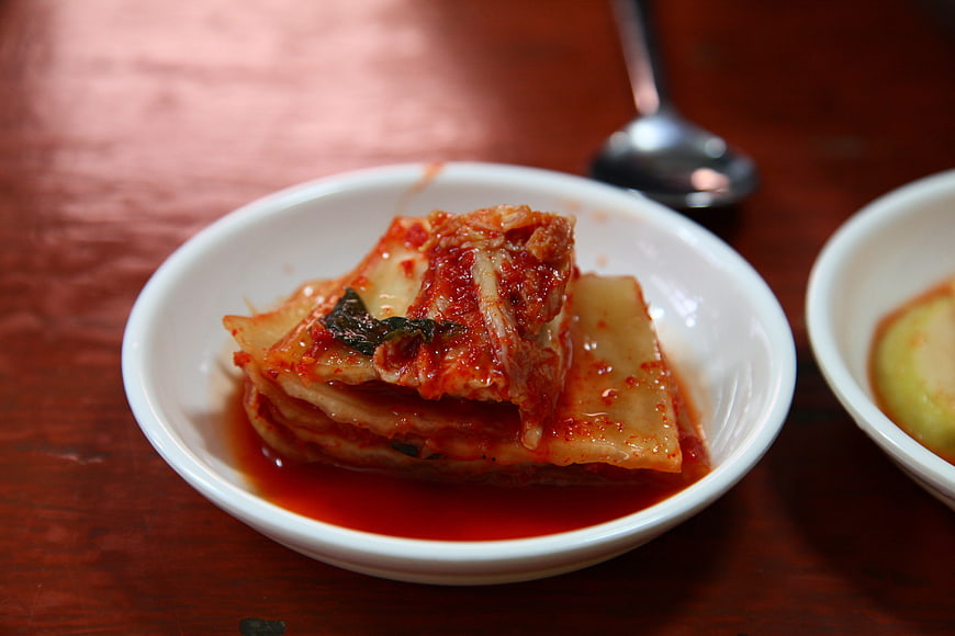 Close-up of spicy kimchi in a white bowl on wooden table