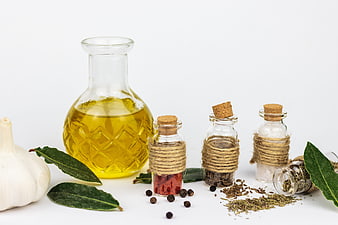 Olive Oil, Garlic, and Spices in Glass Bottles on White Background
