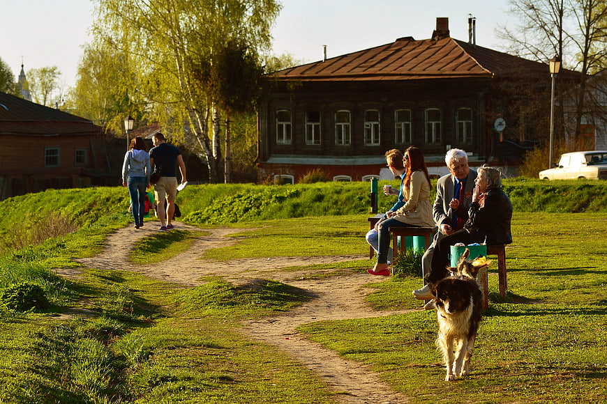 Elderly couple and dog in a sunny Russian village park