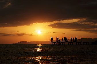 Silhouettes of People Fishing on a Pier at Sunset