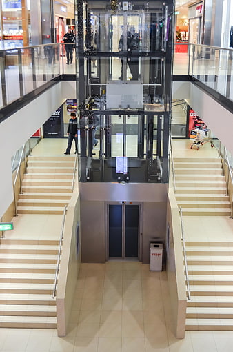 Modern glass elevator in shopping mall with stairs