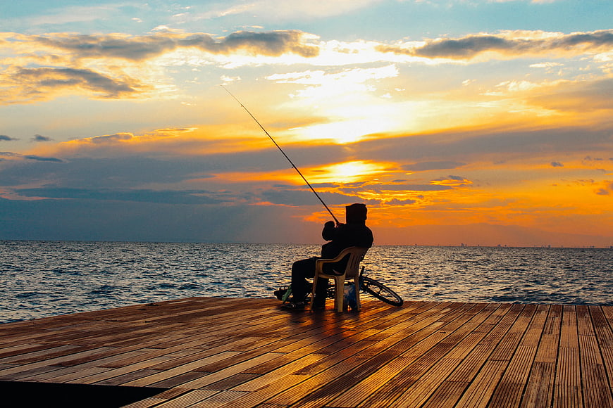 Silhouette of Fisherman on Wooden Pier at Sunset