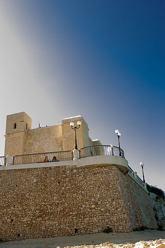 Low angle view of historic stone fortress against blue sky