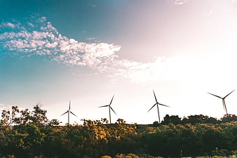 Wind Turbines on Green Hillside Against Blue Sky