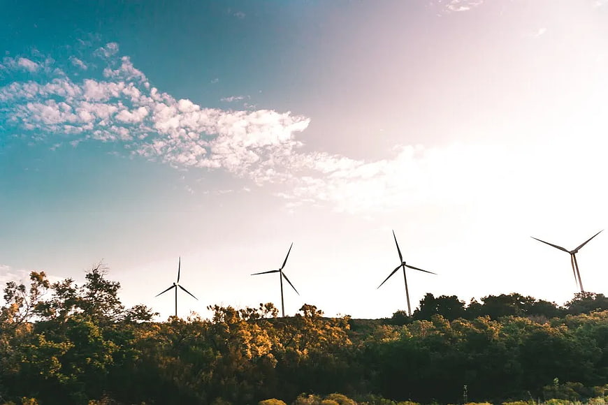 Wind Turbines on Green Hillside Against Blue Sky