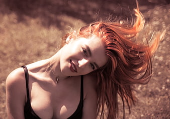Portrait of smiling redhead woman with windblown hair outdoors