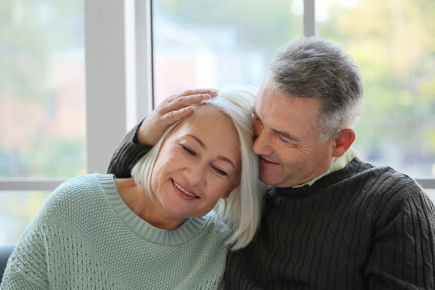 Senior couple embracing affectionately by window