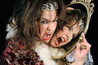 Angry woman screaming at mirror reflection in red velvet costume