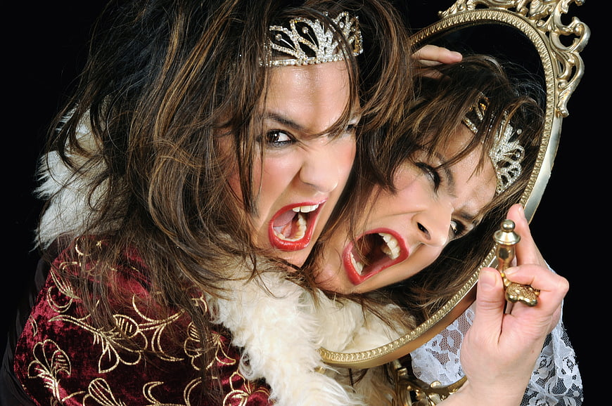 Angry woman screaming at mirror reflection in red velvet costume