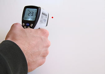 Hand Holding Infrared Thermometer Measuring Wall Temperature