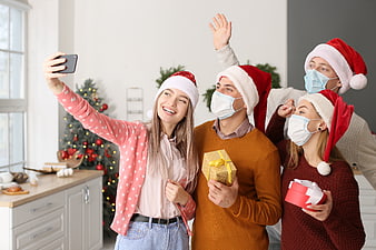 Happy friends taking selfie with masks at Christmas