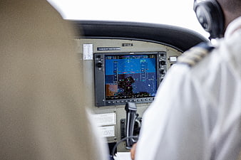 Pilot in cockpit with flight instruments and navigation screen