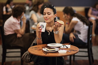 Woman enjoying coffee and cake at a busy cafe