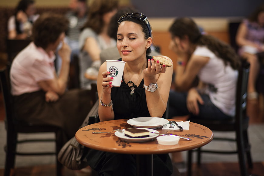Woman enjoying coffee and cake at a busy cafe