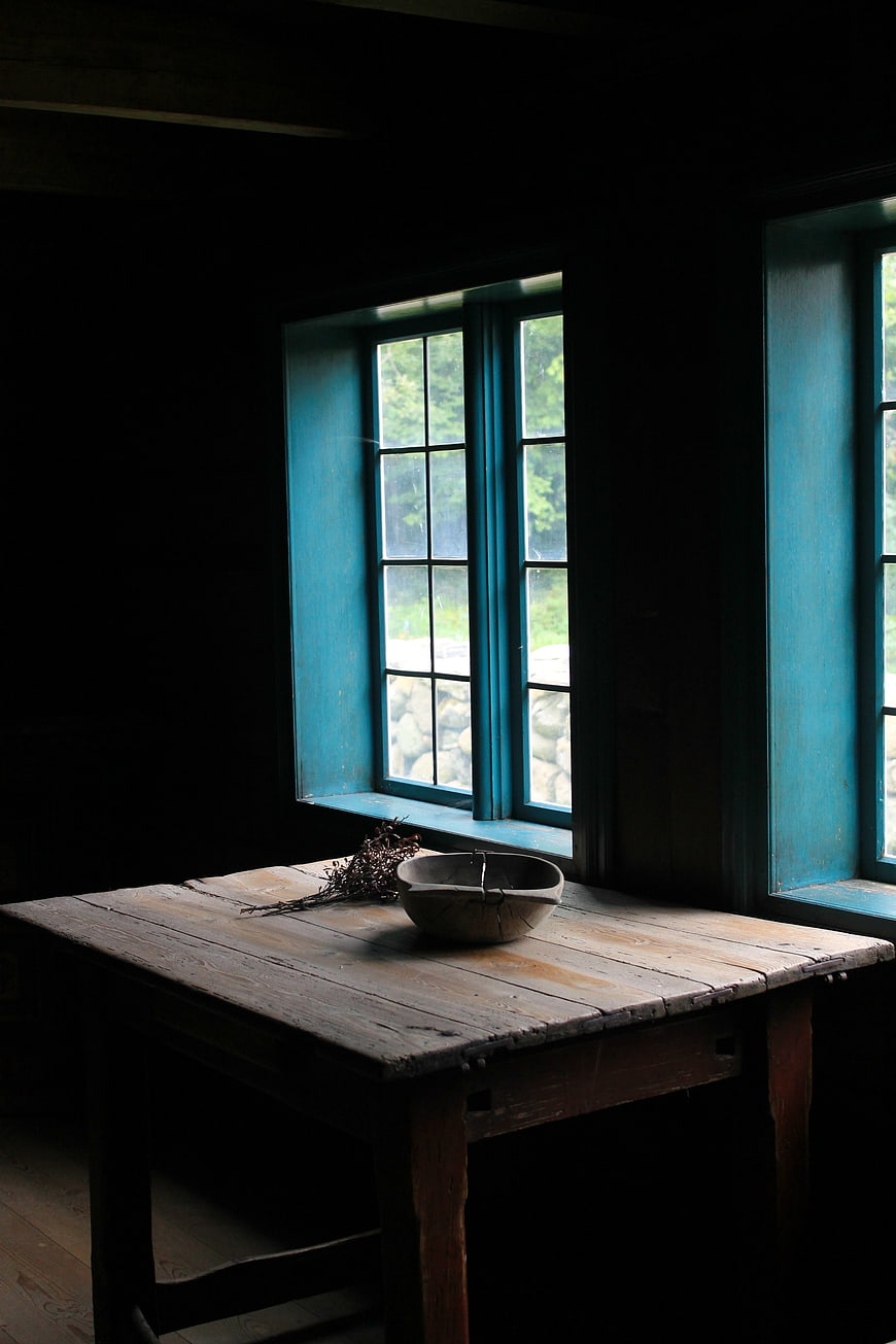 Rustic wooden table with bowl near blue window