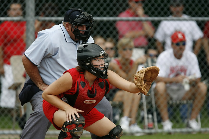 Female Softball Catcher in Red Gear Crouching