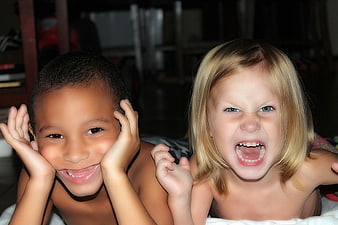 Two children making funny faces and expressions indoors
